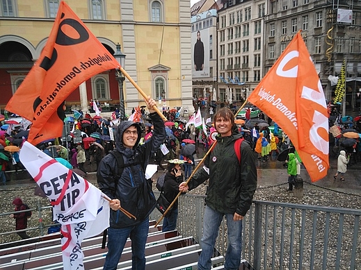Manfred und Florian Reinhart schwenken ÖDP-Fahnen, im Hintergrund der Demo-Zug